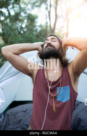 Ritratto di uomo nella parte anteriore della tenda ascoltando la musica con gli auricolari Foto Stock