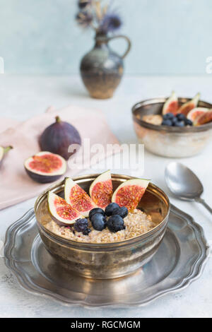 Ciotola di porridge con fette di fichi, mirtilli e frutti di bosco essiccati Foto Stock