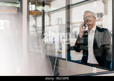 Manager di parlare al telefono in high tech company Foto Stock