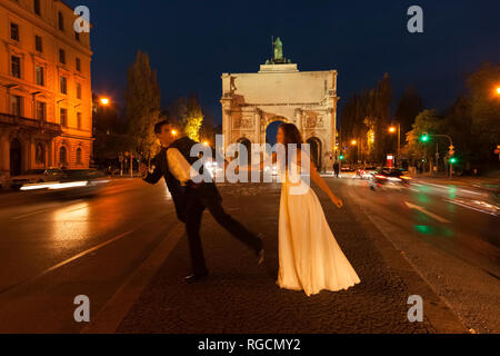 Felice coppia di sposi attraversando Leopold Street a Monaco di Notte Foto Stock