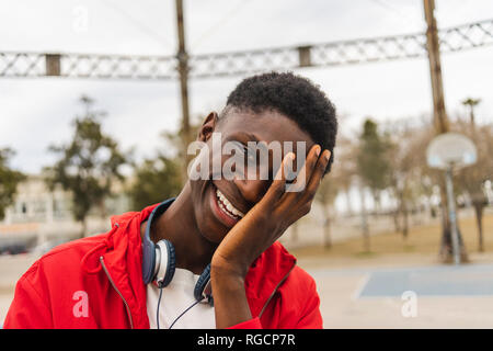 Ritratto di un giovane uomo nero, ridendo con la mano sul suo viso Foto Stock