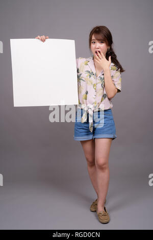 Donna asiatica holding vuoto lavagna bianca con copyspace Foto Stock