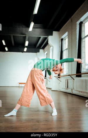 Bella slim yoga pulmann in un verde turtleneck facendo arching Foto Stock