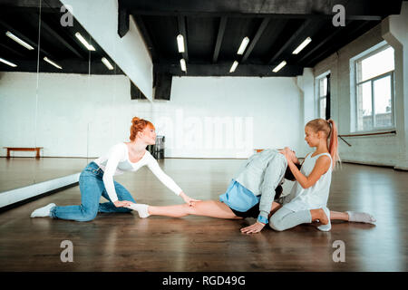 I capelli rossi insegnante di ginnastica in jeans blu sorridente piacevolmente ai suoi studenti Foto Stock