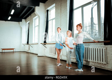 I capelli rossi ballet insegnante e i suoi studenti in piedi la terza posizione di balletto Foto Stock