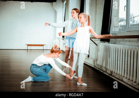 I capelli rossi insegnante di balletto in blue jeans di correzione della posizione dei piedi Foto Stock