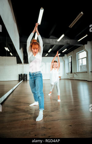 I capelli rossi insegnante di danza e il suo allievo alzando le mani in aria Foto Stock