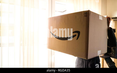 Parigi, Francia - Dic 25, 2018: Donna tenendo vicino alla porta di vetro grandi Amazon parcel scatola di cartone sul giorno di Natale con grande enorme dono all'interno Foto Stock