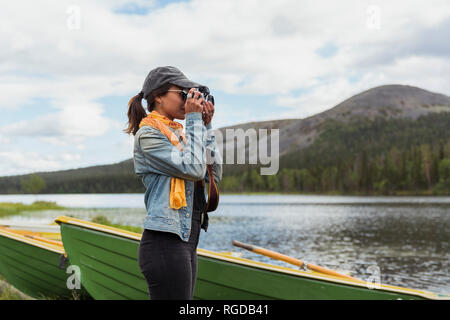 Finlandia, Lapponia, donna di scattare una foto con una fotocamera a lago Foto Stock