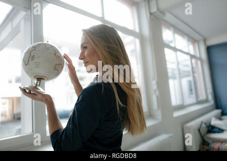 Sorridente giovane imprenditrice holding globe Foto Stock