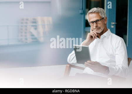 Manager seduto in ufficio utilizzando la tavoletta digitale Foto Stock