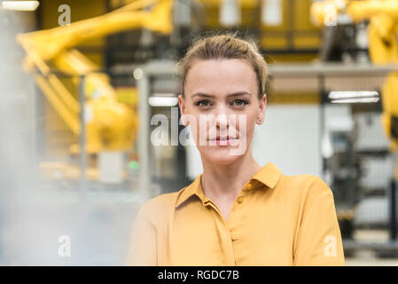 Ritratto di donna fiducioso nel negozio della fabbrica piano con robot industriale Foto Stock