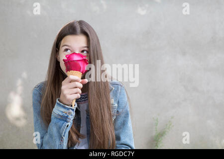 Ragazza odore di rosa rosa blossom nel cono gelato con Foto Stock