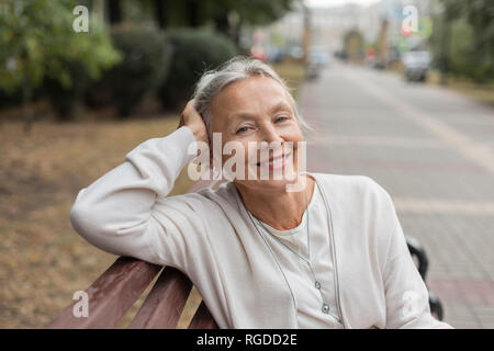 Ritratto di sorridente donna senior relax su un banco di lavoro Foto Stock