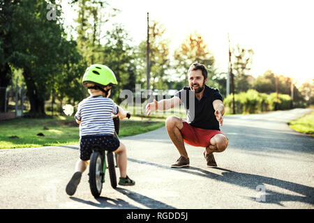 Padre il supporto piccolo figlio in bici Foto Stock