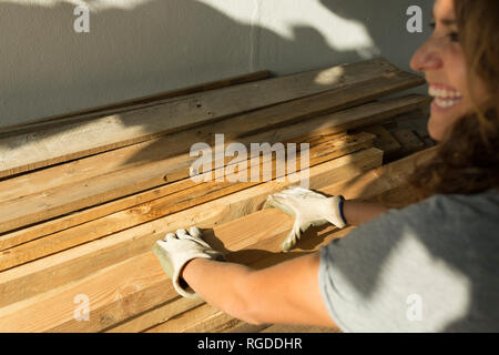 Felice craftswoman indossando guanti protettivi per la lavorazione del legno Foto Stock