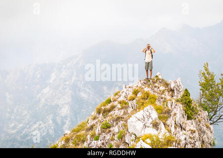 L'Italia, Massa, uomo in piedi sulla sommità di un picco nelle Alpi Apuane montagne Foto Stock