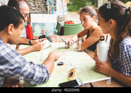 Gruppo di escursionisti seduti insieme la pianificazione di un percorso escursionistico guardando alla mappa Foto Stock