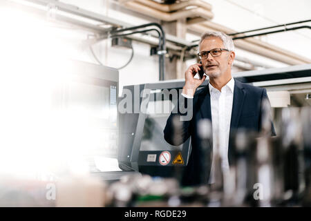 Manager di parlare al telefono in high tech company Foto Stock