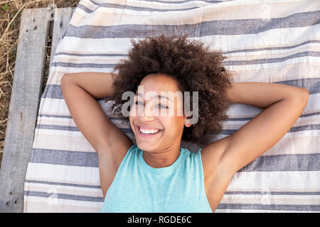 Ritratto di donna felice giacente su una coperta all'aperto Foto Stock