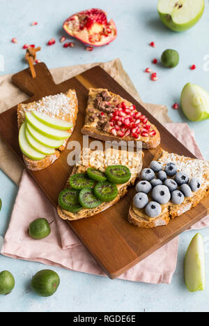 Fette di pane con vari ingredienti sulla tavola di legno Foto Stock