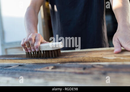 Craftswoman utilizzando pennello sul pezzo di legno Foto Stock