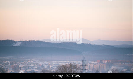 Alba d'inverno e il pupazzo di neve nebbia. Il sole sorge su una piccola città. Mattina nella città settentrionale Foto Stock