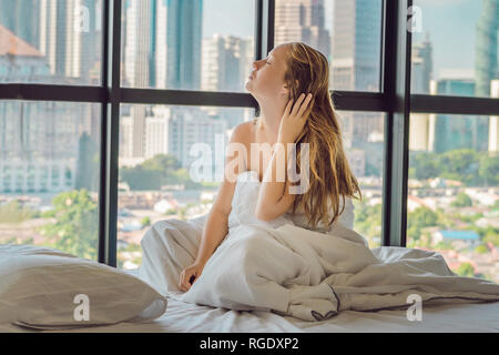 La donna si sveglia la mattina in un appartamento nella zona del centro cittadino con una vista dei grattacieli. La vita in il rumore della città grande concetto. Non Foto Stock