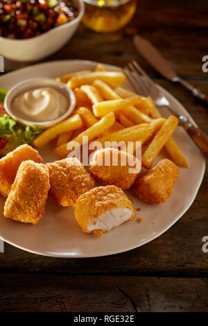 Saporiti frutti di mare snack o antipasto di fritti kibbeling o morso dimensioni porzioni di baccalà fritto servito con patate fritte, insalata e maionese Foto Stock