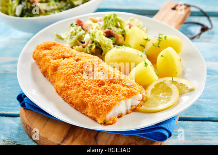 Pezzo di fresco panato croccante pesce con patate servita su piastra Foto Stock