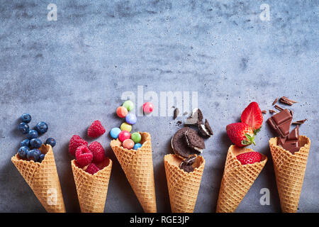 Ingredienti per specialità di gelato fuoriuscita da rocche su una trama di grigio ardesia con sfondo oreos, fragole, lamponi mirtilli, sug Foto Stock