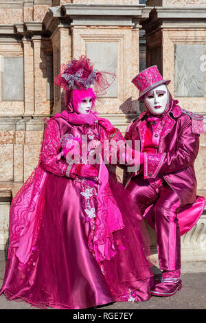 I partecipanti non identificato vestono i tradizionali costumi colorati e maschere bianche durante il famoso Carnevale che si svolge a Venezia. Foto Stock