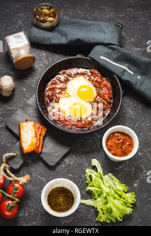 Shakshuka, uova fritte in salsa di pomodoro in ferro padella. Israele tipico cibo. Foto Stock