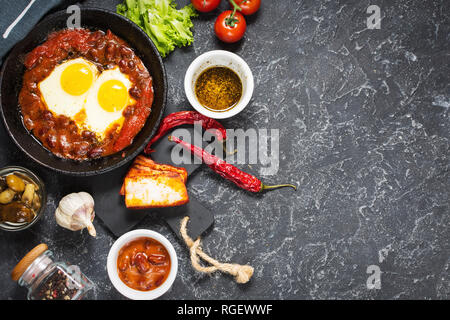 Shakshuka, uova fritte in salsa di pomodoro in ferro padella. Israele tipico cibo. Vista superiore e spazio di copia Foto Stock