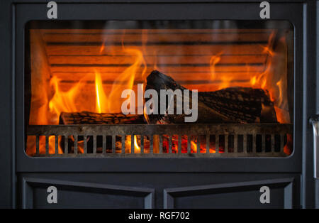 Il fuoco brucia in un metallo nero antico caminetto Foto Stock