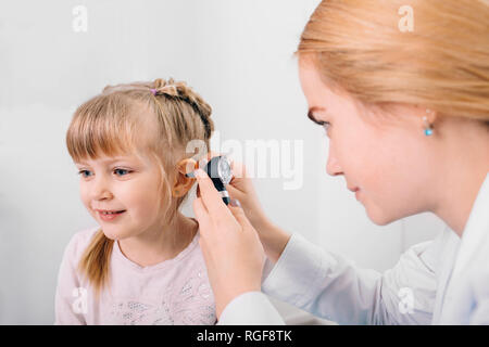 Sorridente bambina avente orecchio esame con otoscopio Foto Stock