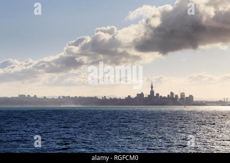 Misty contorno di Auckland visto dall'acqua, incluso Sky Tower. Carattere distintivo la formazione di nubi nel cielo. Foto Stock