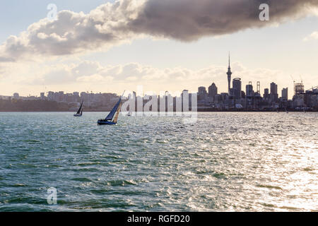 Silhouette contorno di Auckland visto dall'acqua, incluso Sky Tower. Barche a vela in primo piano. Foto Stock