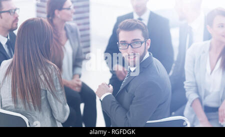 Giovane lavoratore seduto in un cerchio di colleghi Foto Stock