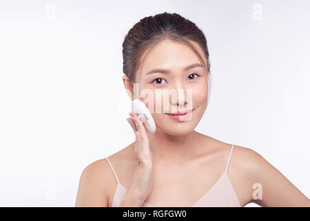 Sorridente ragazza con cuscino in polvere puff applicando polvere cosmetica sulla faccia Foto Stock