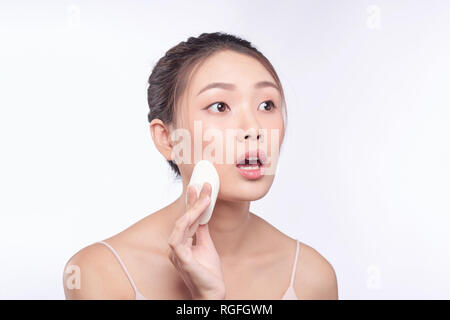 Donna con sorpresa di fronte mettendo sul make up, liquido applicato foundation sul suo viso Foto Stock