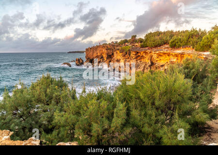 I visitatori si sono riuniti su una roccia a guardare il tramonto sull'oceano, Poipu, Koloa, Kauai, Hawaii Foto Stock