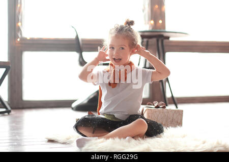 Piccolo felice ragazza seduta sul tappeto in salotto. Foto Stock