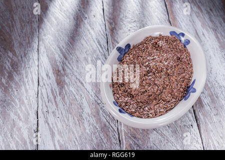 Semi di lino nel recipiente, sul legno vecchio Foto Stock