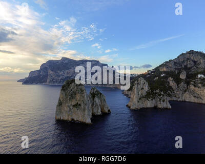 Faraglioni torreggianti fino dal blu luminoso acque del Mediterraneo sull'isola di Capri, Italia Foto Stock