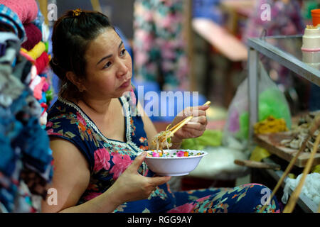 Donna di mangiare cibo di strada con bacchette di Dong Ba market in tinta, Vietnam, Asia Foto Stock