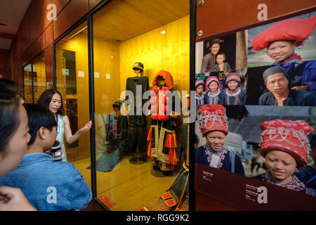 Tour con guida che mostra la modalità DAO popolare di vestiti per i turisti mentre visitano il Vietnam Museo di Etnologia di Hanoi, Vietnam, sud-est asiatico Foto Stock