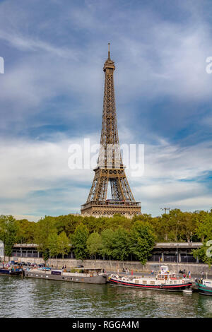 La Torre Eiffel sorge sopra il fiume Senna ,con barche in primo piano ormeggiate lungo la riva del fiume , Parigi Foto Stock