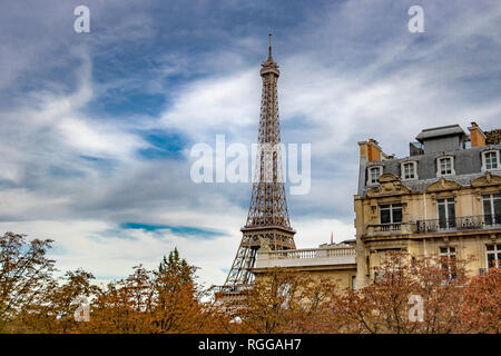 La Torre Eiffel si siede dietro un grande appartamento di Parigi edificio come visto da Avenue de Camoens con gli alberi girando un autunnale di colore arancione , Parigi Foto Stock