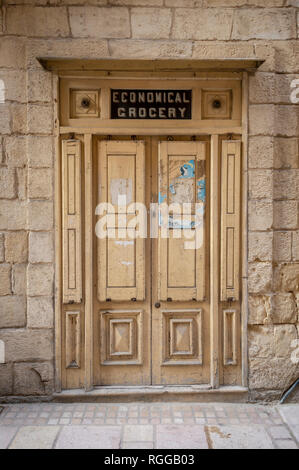 "Economico" di generi alimentari di porte in legno impostato in edificio di pietra calcarea in Vittoriosa, Birgu, Malta. Foto Stock